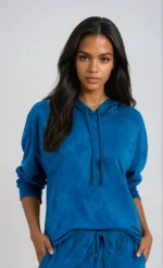 A woman wearing a matching blue hoodie and jogging bottoms set on a grey background