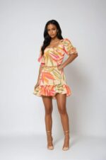 Woman wearing a multicoloured tropical floral dress and gold high-heeled shoes
